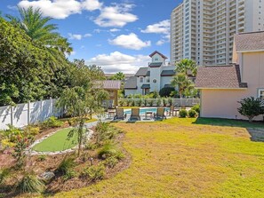 A residential area with a swimming pool, lounge chairs, and a fenced yard.