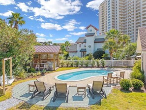 A residential area with a swimming pool, outdoor seating, and a gazebo.