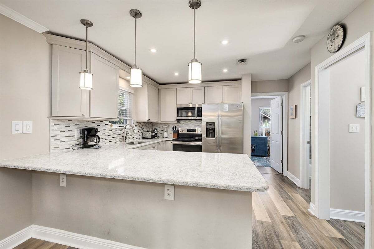A modern kitchen with a central island, pendant lighting, and stainless steel appliances.