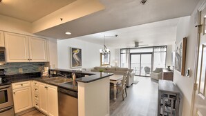 Eine moderne Küche mit weißen Schr änken, einem Geschirrspüler und einer Arbeitsplatte aus Granit. Ein Essbereich mit Tisch und Stühlen sowie ein Wohnzimmer mit Sofa und Couchtisch sind ebenfalls vorhanden.