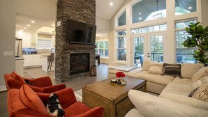 Una sala de estar moderna con chimenea de piedra, un televisor grande y una zona de estar cómoda con sofá y sillones.