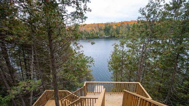 Una terraza de madera con vista a un lago rodeado de árboles.