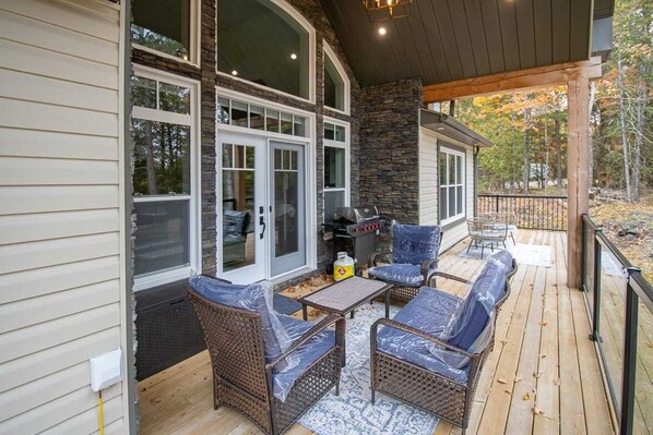 A covered patio area with wicker furniture and a grill.