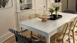 A modern kitchen with white cabinetry, a stainless steel refrigerator, and a dining area with a white table and patterned chairs. - Gem on Spring-Upscale home walk to Main sleeps 11 (Del Rio)