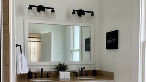 A bathroom with a double sink vanity, a large mirror, and a hexagonal tile floor. - Gem on Spring-Upscale home walk to Main sleeps 11 (Del Rio)