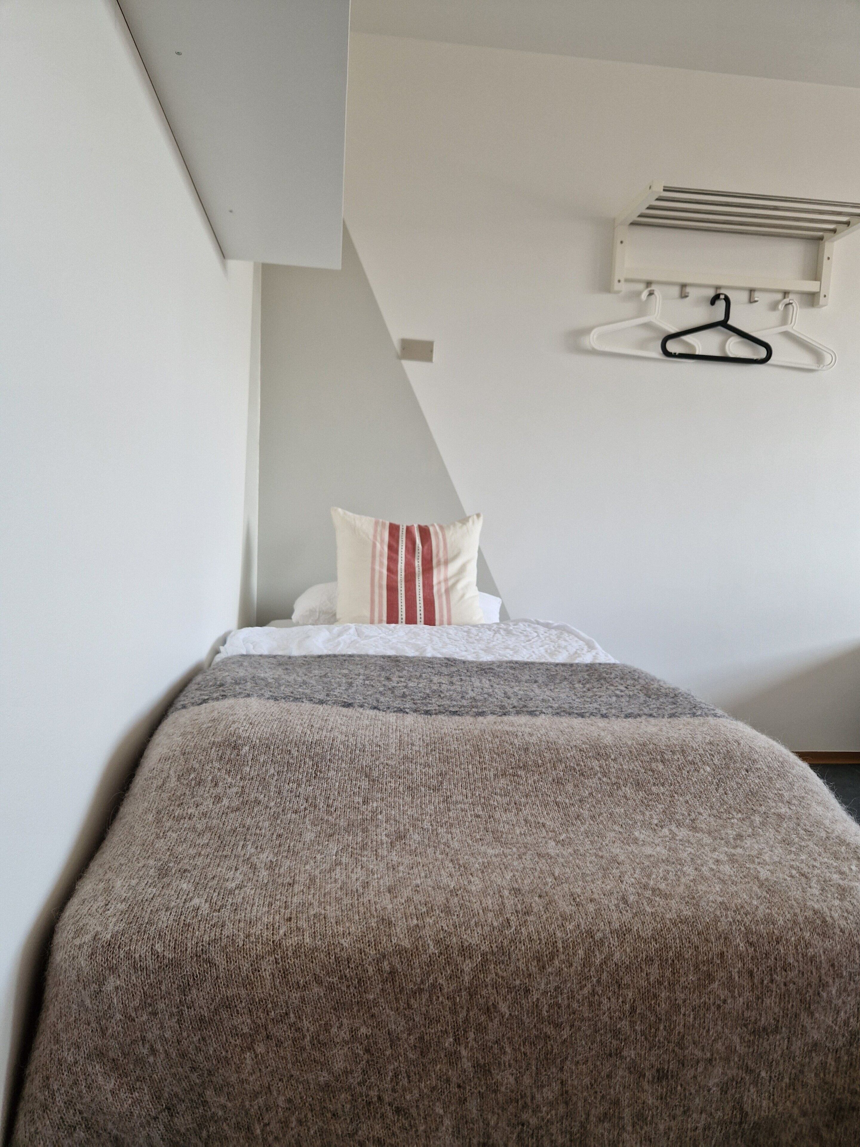 Une chambre avec un lit, un portant à vêtements et un plafond en pente.