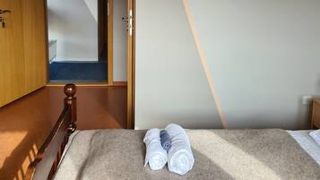 A bedroom with a bed, a wooden headboard, a carpeted floor, and a door leading to another room.