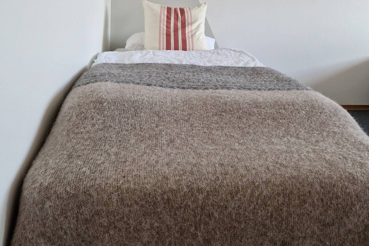 Un dormitorio con cama, perchero y techo inclinado.