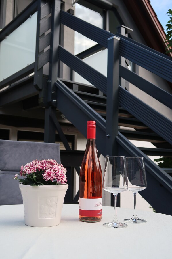 A bottle of wine and two glasses on a table with a potted plant.