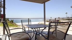 Een overdekt terras met uitzicht op het strand en de oceaan.