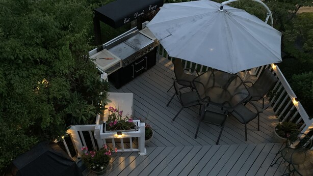 Una terraza con parrilla, asientos al aire libre y plantas en macetas.