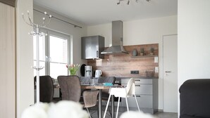 Een moderne keuken met een eethoek, met een centraal eiland, een inbouwfornuis en een groot raam.