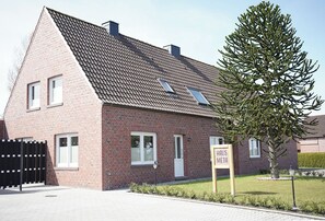 Ein rotes Backsteinhaus mit geneigtem Dach, einem schwarzen Tor und einem Schild mit der Aufschrift 'HAUS META'.