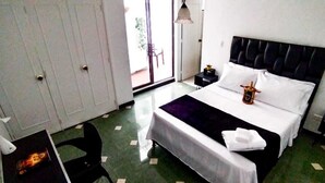 A hotel room with a bed, a chair, a nightstand, and a small table.