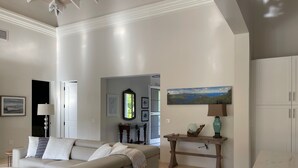 A modern living room with a beige sofa, a wooden coffee table, and a painting of a landscape. - Welcome to your island home, Mystical Mermaid! (Cruz Bay)