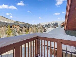 A snow-covered balcony with a view of a mountain resort.
