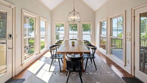 A dining area with a long wooden table, black chairs, and a hanging light fixture.