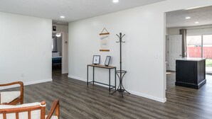 A spacious living area with hardwood flooring, a coat rack, a small table with two framed pictures, and a door leading to another room. - Central Location- Updated 3 Bed 2 Bath (Xenia)