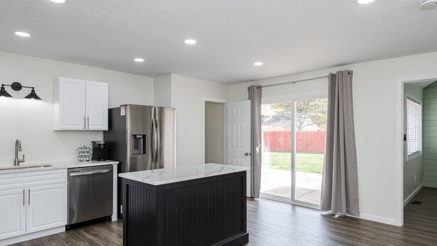 A modern kitchen with white cabinets, stainless steel appliances, and a dark island. - Central Location- Updated 3 Bed 2 Bath (Xenia)