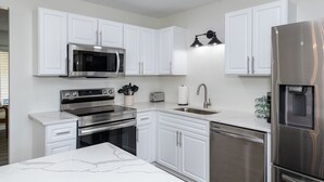 A modern kitchen with white cabinets, stainless steel appliances, and a marble countertop. - Central Location- Updated 3 Bed 2 Bath (Xenia)