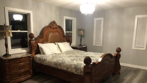 Een slaapkamer met een houten hemelbed, een nachtkastje met een lamp en een kaptafel.