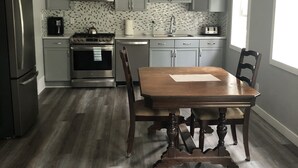 Een moderne keuken met grijze kastjes, een houten eettafel en een roestvrijstalen koelkast.