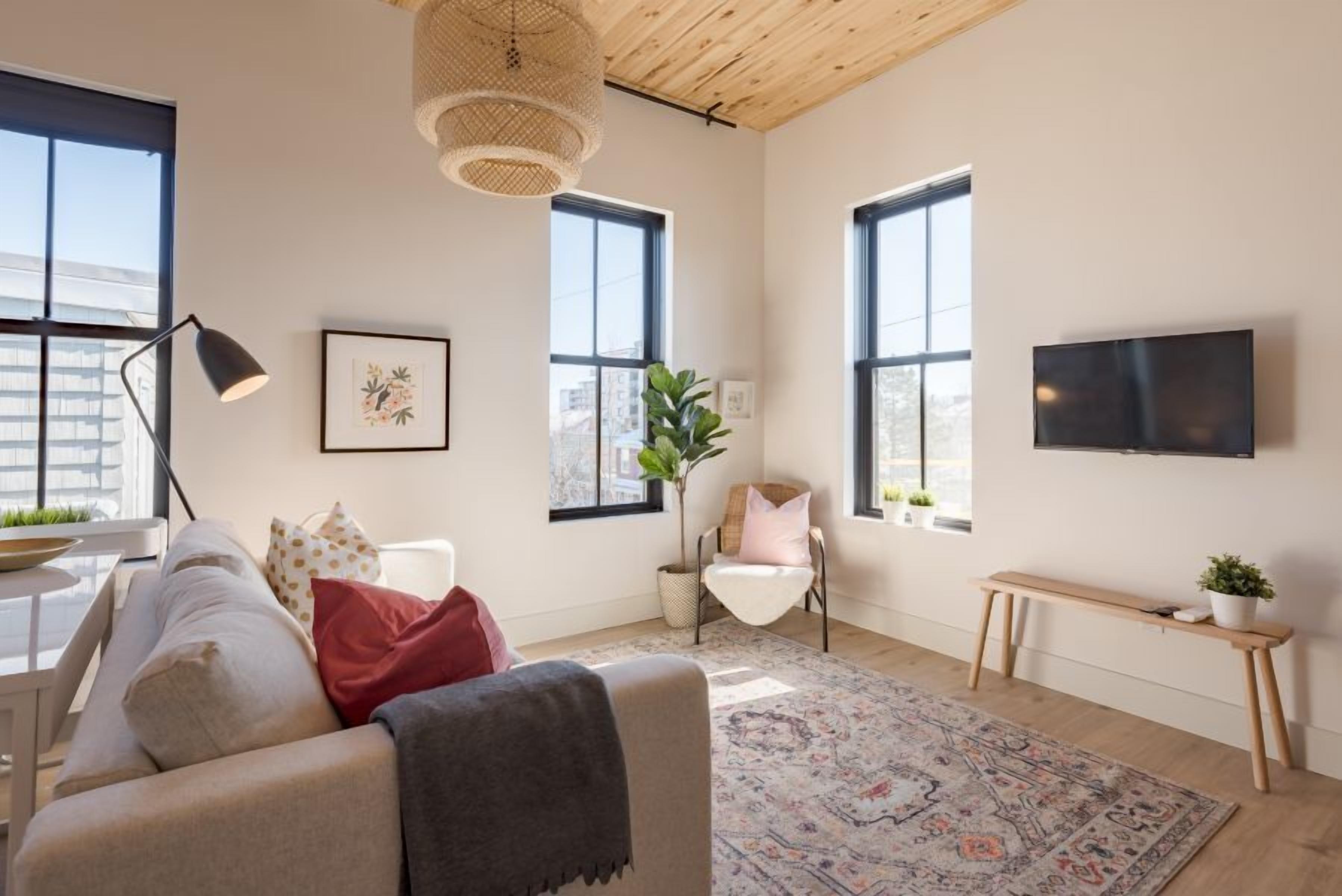 Una sala de estar moderna con un sofá, una mesa de centro, un televisor y un ventanal amplio.