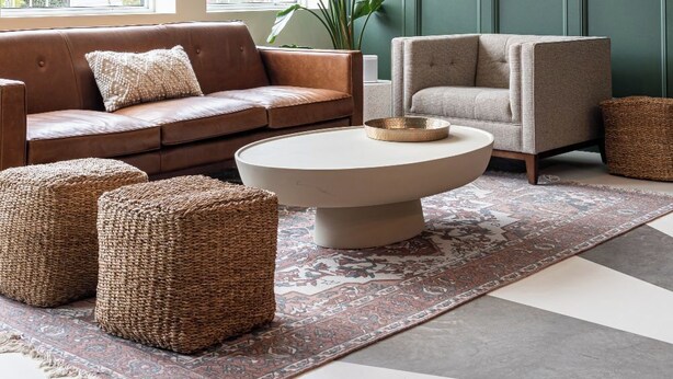 A modern living room with a brown leather sofa, a grey armchair, a round coffee table, and a woven pouf. - Brewery Park Hotel (Halifax)