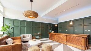 A modern lobby with a wooden reception desk, leather sofas, a round coffee table, and a large green plant. - Brewery Park Hotel (Halifax)