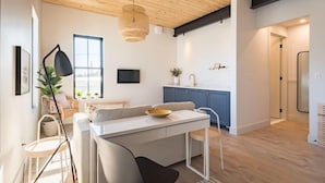 A modern kitchen with white cabinets, a dining area with a white table and chairs, and a large window providing natural light. - Brewery Park Hotel (Halifax)