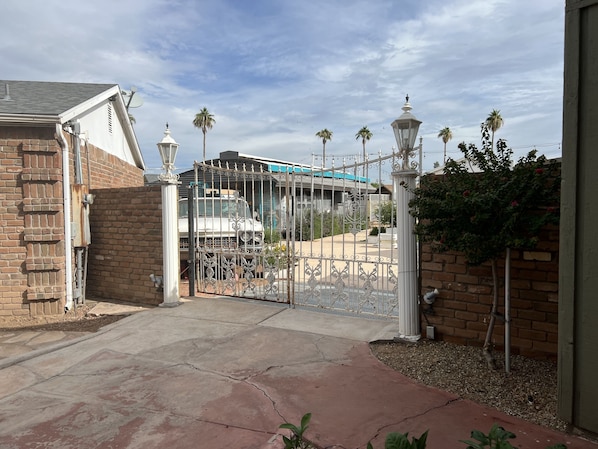 A gated driveway leading to a house with a brick exterior and a garage.