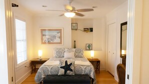 A bedroom with a bed, two bedside tables, a ceiling fan, a window with blinds, a framed picture on the wall, and a dark-colored bench. - Casa Louisa -Beautiful 2 Bedroom in Old Town - Right off Duval/Great Front Porch (Key West)