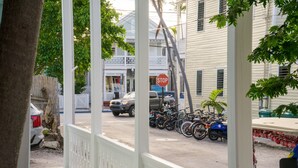 A porch with a stop sign, a parked car, and a row of bicycles. - Casa Louisa -Beautiful 2 Bedroom in Old Town - Right off Duval/Great Front Porch (Key West)