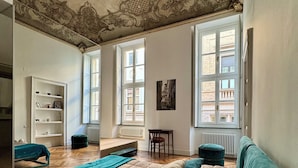 Ein Schlafzimmer mit einem großen Bett, einem Sessel, einem kleinen Tisch und einem Bücherregal.