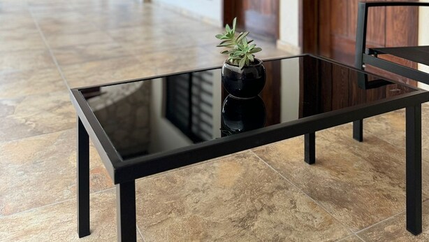 Um interior moderno com uma mesa de vidro, um vaso de planta e portas de madeira.