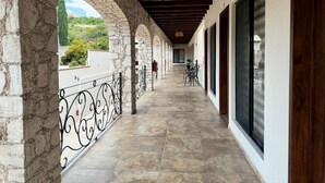 Um corredor coberto com arcos de pedra, piso de azulejos e vista para o verde lá fora.