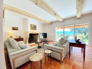 A living room with a fireplace, sofas, a TV, and a view of the outdoors. - Spacious, peaceful villa in 1 hectare grounds near Gordes (Goult)