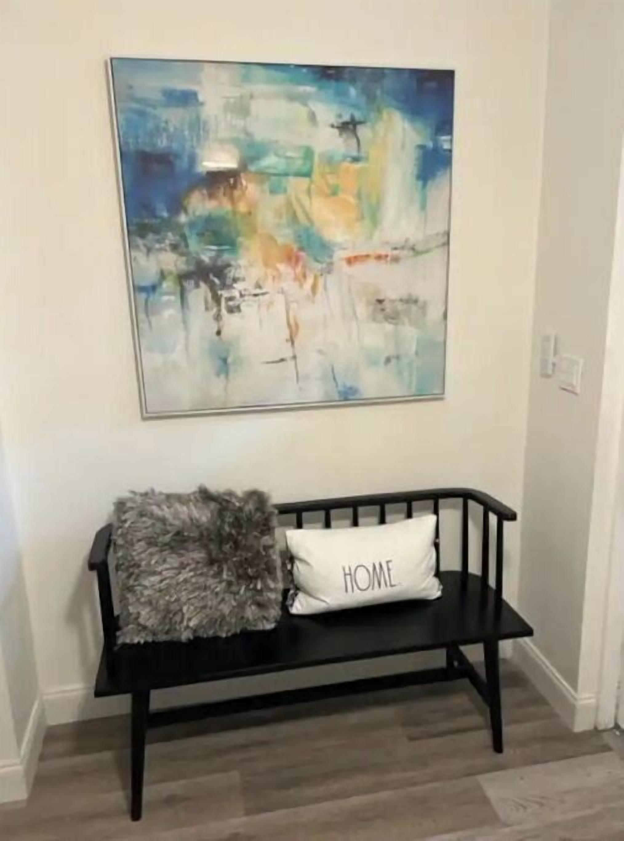Un banc noir avec un coussin blanc sur lequel est inscrit le mot « MAISON » et une couverture grise douce et moelleuse.