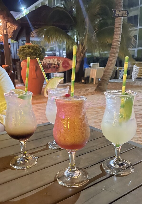 Drie drankjes op een houten tafel met een tropische achtergrond.