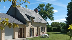 Une maison avec un toit en pente, une allée gravillonnée et une pelouse verdoyante.