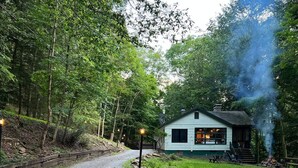 A cabin with a gravel path leading to it, surrounded by trees.