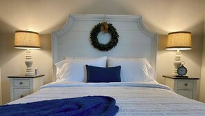 A neatly made bed with a blue blanket, white bedding, and a decorative wreath on the headboard.