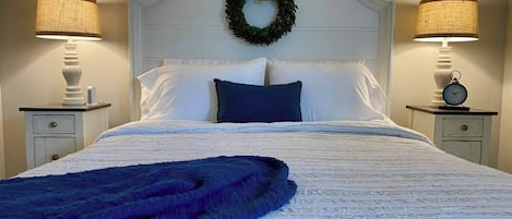 A neatly made bed with a blue blanket, white bedding, and a decorative wreath on the headboard.
