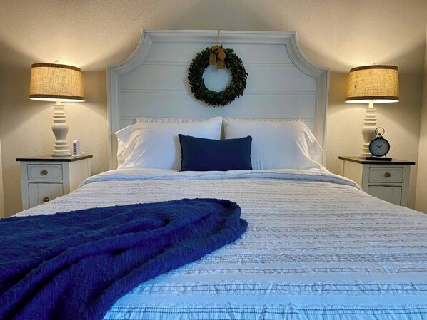 Un lit bien fait, avec une couverture bleue, du linge de lit blanc et une guirlande décorative sur la tête de lit.