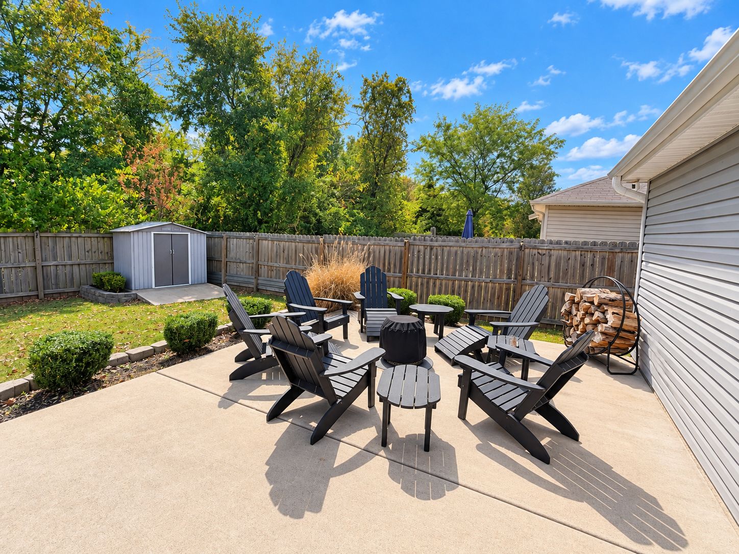 A backyard patio with outdoor furniture, a shed, and a wooden fence.
