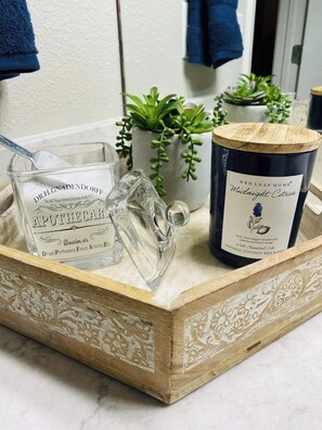 Un plateau en bois sur lequel se trouvent une bouteille en verre portant l’étiquette « DR. H. GNADENDEROFF » et une bougie portant l’étiquette « Red Leaf Home Midnight Citrus ».