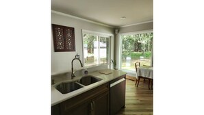 A kitchen with a double sink, wooden cabinets, and a view of the outdoors through large windows. - Hidden Hemlock Retreat Sauna, Spa Tub, Fireplace, 500M Wi-fi, L2+ EV Charger (Carsonville)