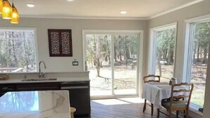 A modern kitchen with a large island, wooden flooring, and a dining area with a table and chairs. - Hidden Hemlock Retreat Sauna, Spa Tub, Fireplace, 500M Wi-fi, L2+ EV Charger (Carsonville)