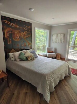 Une chambre avec un grand lit, une fenêtre et un tableau accroché au mur.