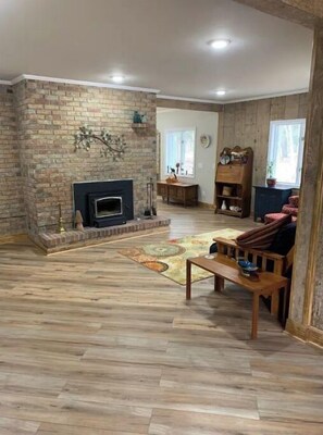 Cozy seating area with a rustic fireplace and wooden floor.